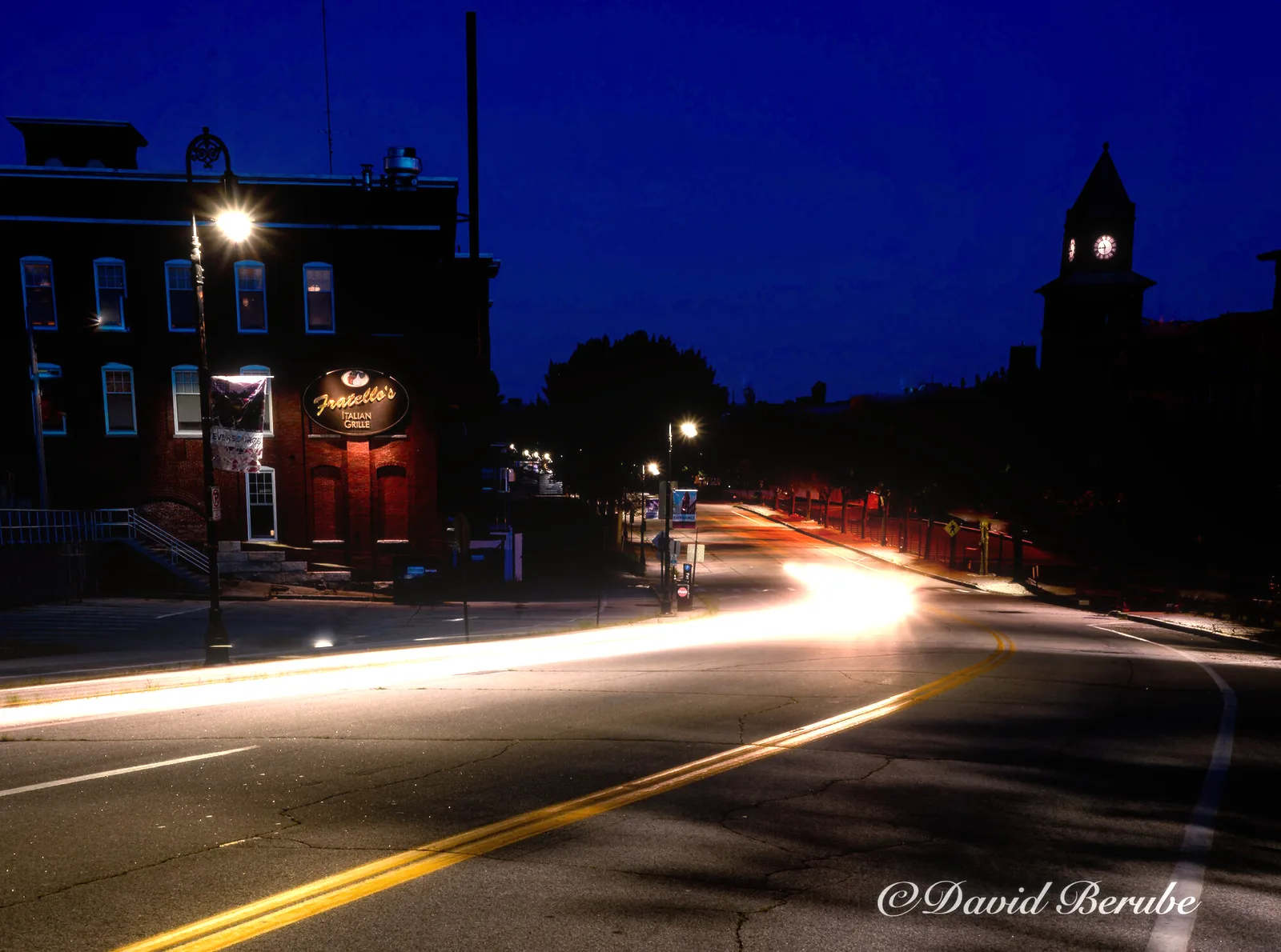 Night street with a moderate glow around the lamps and light trails.